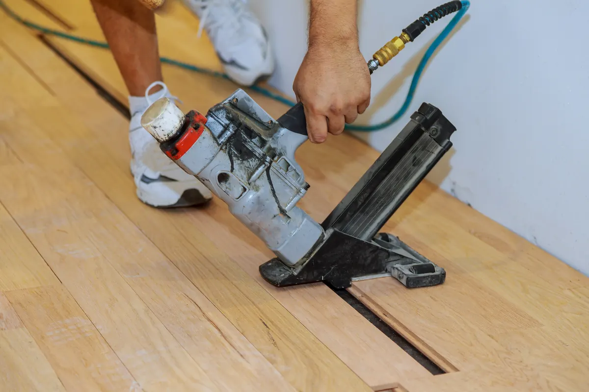 Installer fastening hardwood flooring with a nail gun