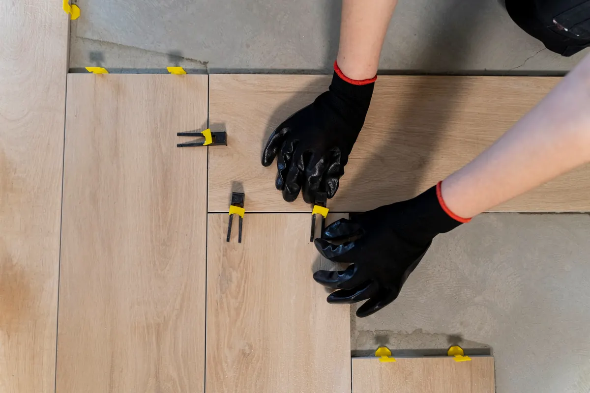 Installer's hands setting floor tile, seen from above