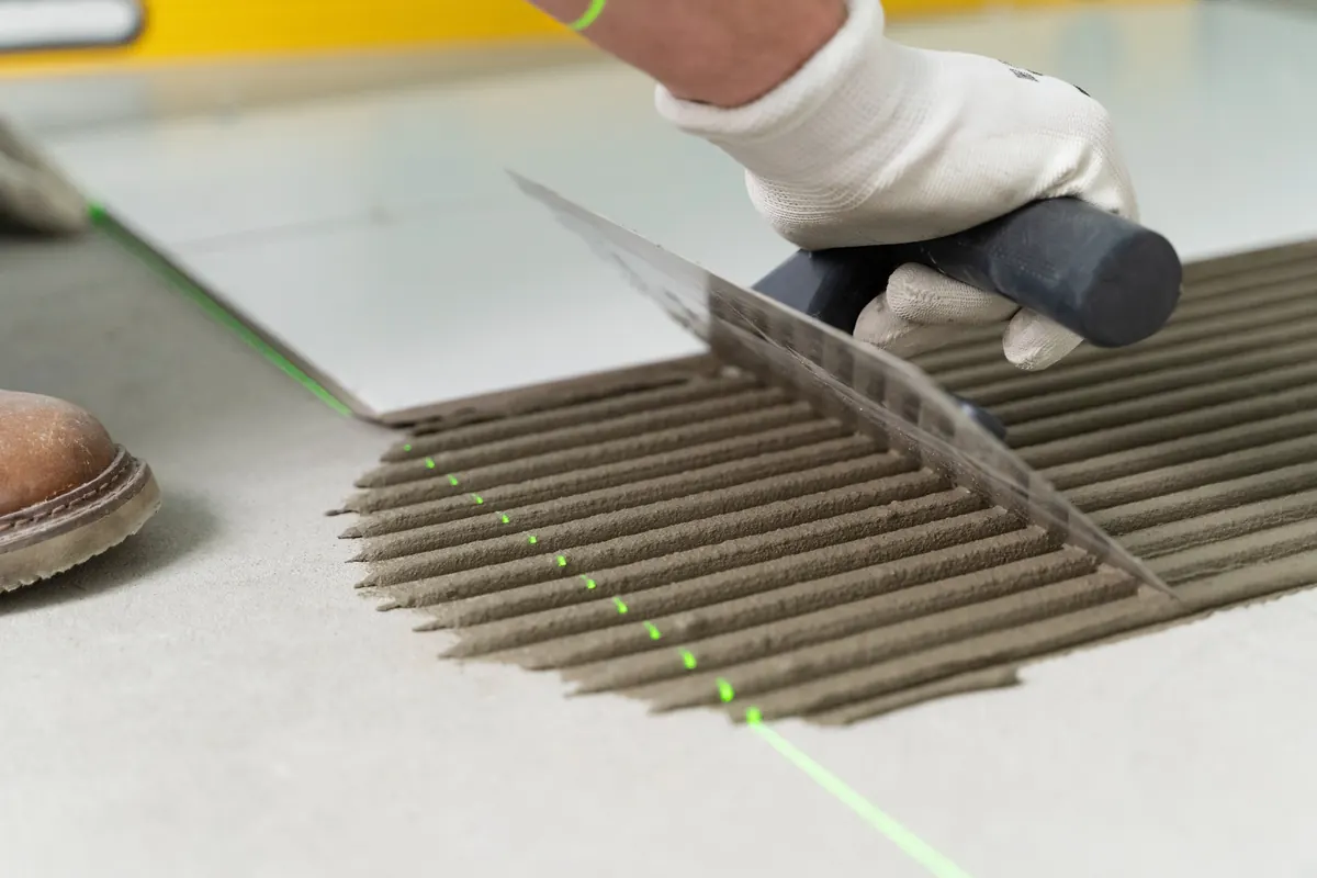 Tile installer measuring a room with a laser during a renovation