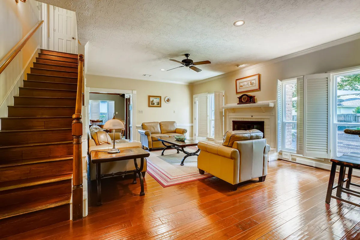 Clean wood floor and staircase in a sunlit living room with plantation shutters