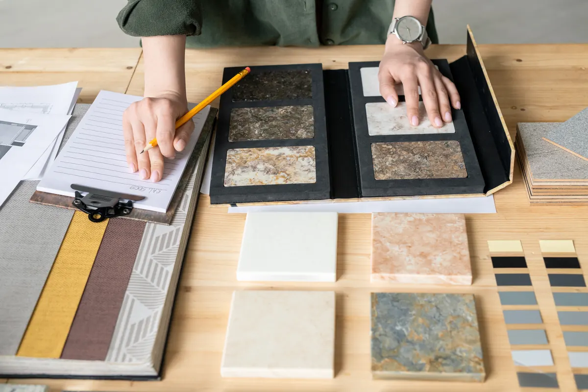 Homeowner taking notes next to tile and stone samples before hiring an installer
